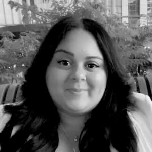 A black and white portrait of Marian Chalas, a Hispanic woman with long dark hair.