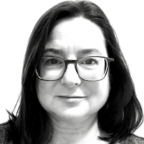 Susan Pavliscak, a light-skinned woman with dark shoulder-length hair wearing square-framed glasses.